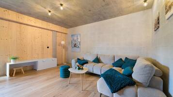 Un salon moderne avec un plancher en bois, un canapé avec des coussins bleus, une table basse blanche et un banc.