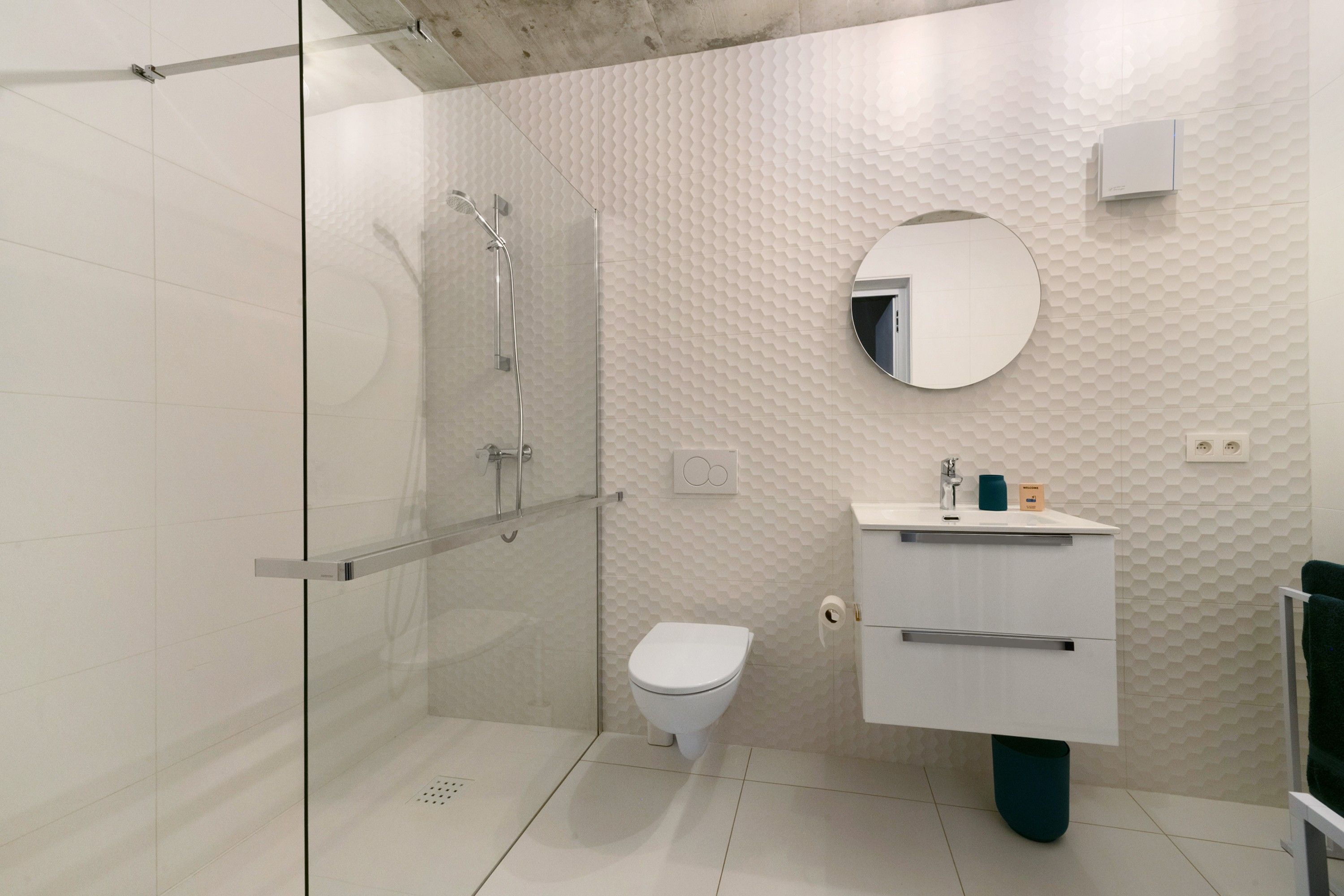 Une salle de bain moderne avec une douche à parois de verre, des toilettes blanches et un meuble-lavabo avec un miroir.