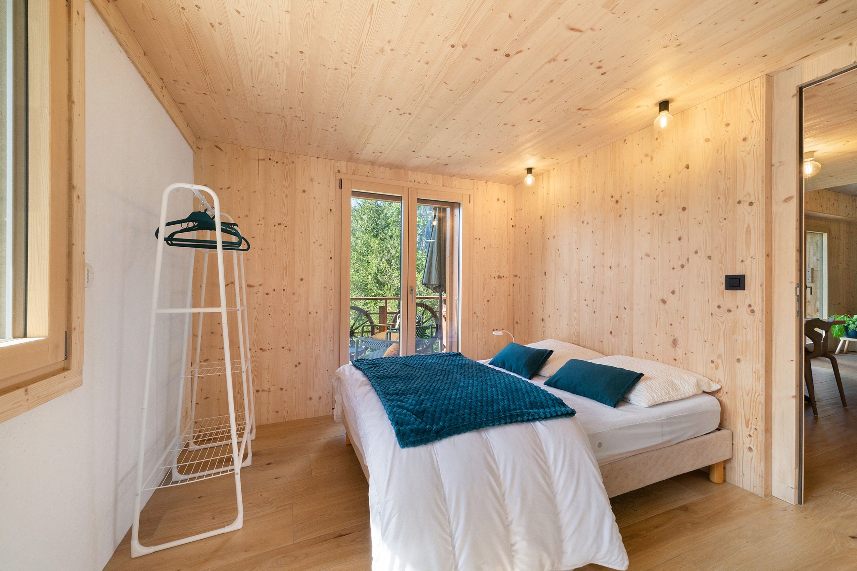Une chambre à coucher avec un lit, un fauteuil suspendu et une fenêtre.