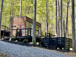 Una cabana amb façana de fusta, una porta vermella i un petit porxo.