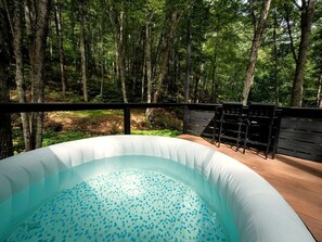 An inflatable hot tub surrounded by a wooden deck and a forested area. - Creekside Glass Suite - Unit 2 (Pet Friendly) (Mars Hill)