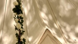 Un alloggio in tenda con un letto, cuscini e una pianta decorativa.