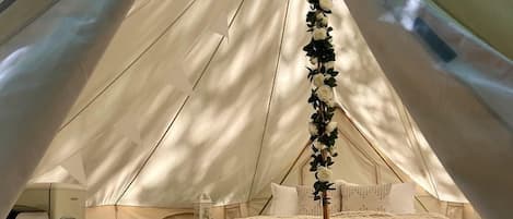 A tent with a bed, a small table, and a refrigerator.