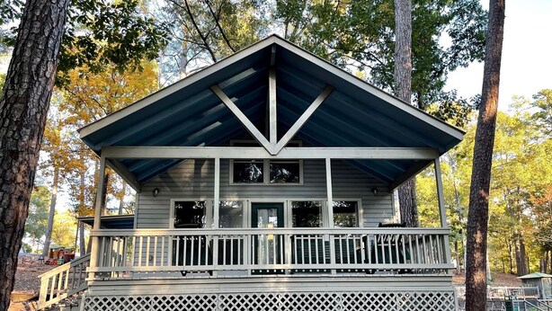 A cabin with a covered porch, a staircase, and a lattice railing.