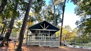 A cabin with a porch, surrounded by trees.
