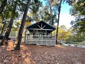 Een chalet met veranda, omgeven door bomen.
