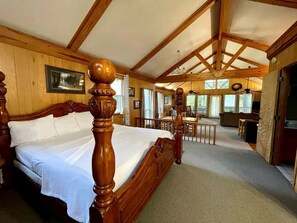 Een slaapkamer met houten frame, een groot bed, een zithoek en uitzicht op de omgeving.