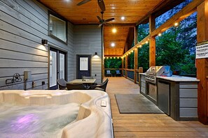 Eine Holzterrasse mit Whirlpool, Grill und Essbereich.
