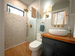 Une salle de bain avec une douche, des toilettes, un lavabo et une fenêtre.