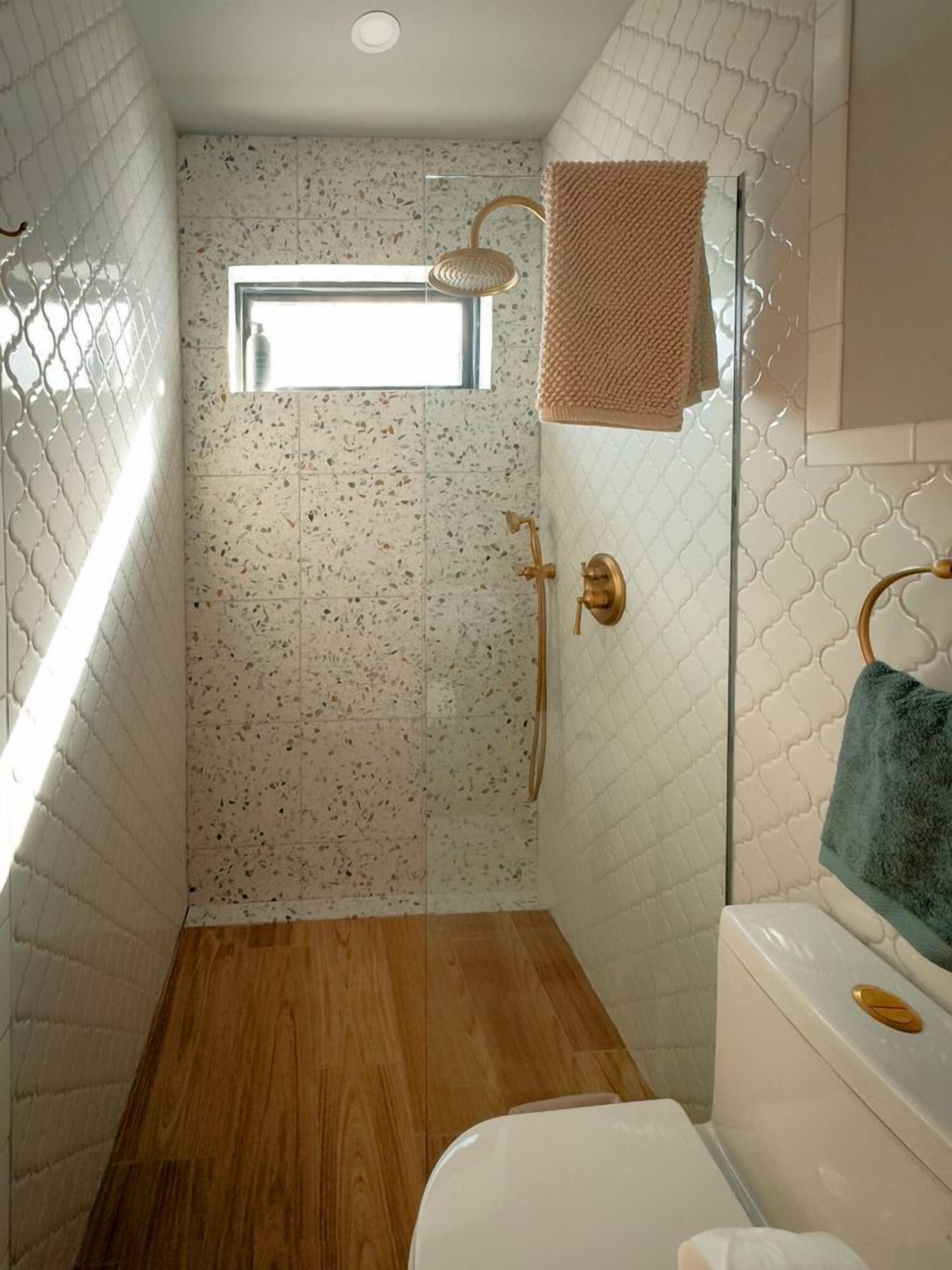 A bathroom with a shower, a toilet, and a window.