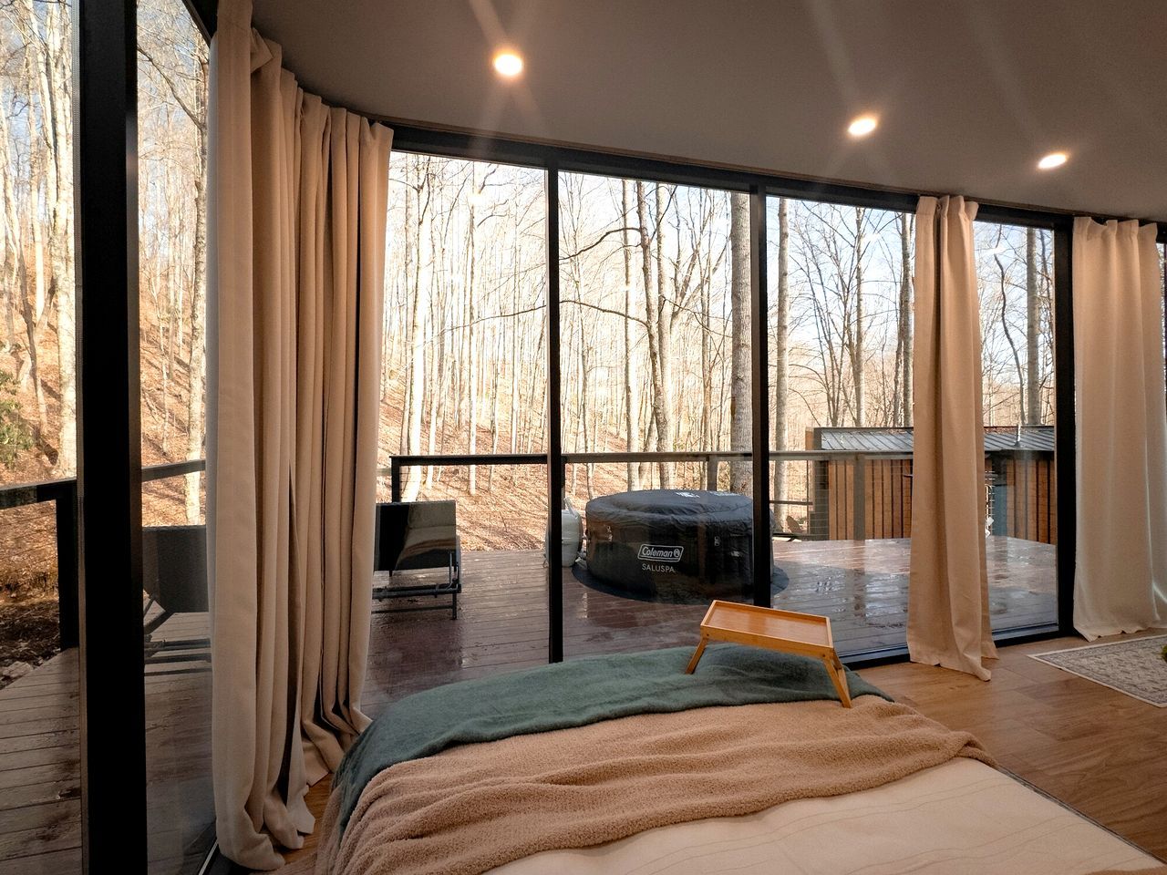 Een slaapkamer met een groot raam, een bed, een stoel en een jacuzzi.
