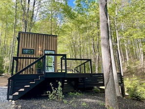 Eine Holzhütte mit einer Treppe, die zu einer Terrasse führt, umgeben von Bäumen.