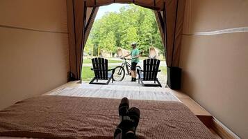 A tent with a view of a person on a bicycle outside, a chair, and a table.