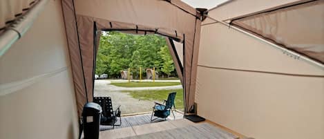 A tent with a view of a park and outdoor seating.