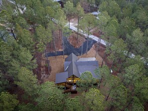 Eine Hütte, umgeben von dichtem Wald, mit freiem Blick auf die umliegenden Bäume und einer Straße im Hintergrund.