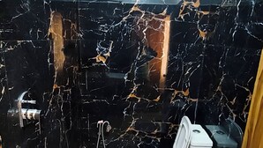 Un baño con inodoro, lavamanos, ducha y un cubo azul.