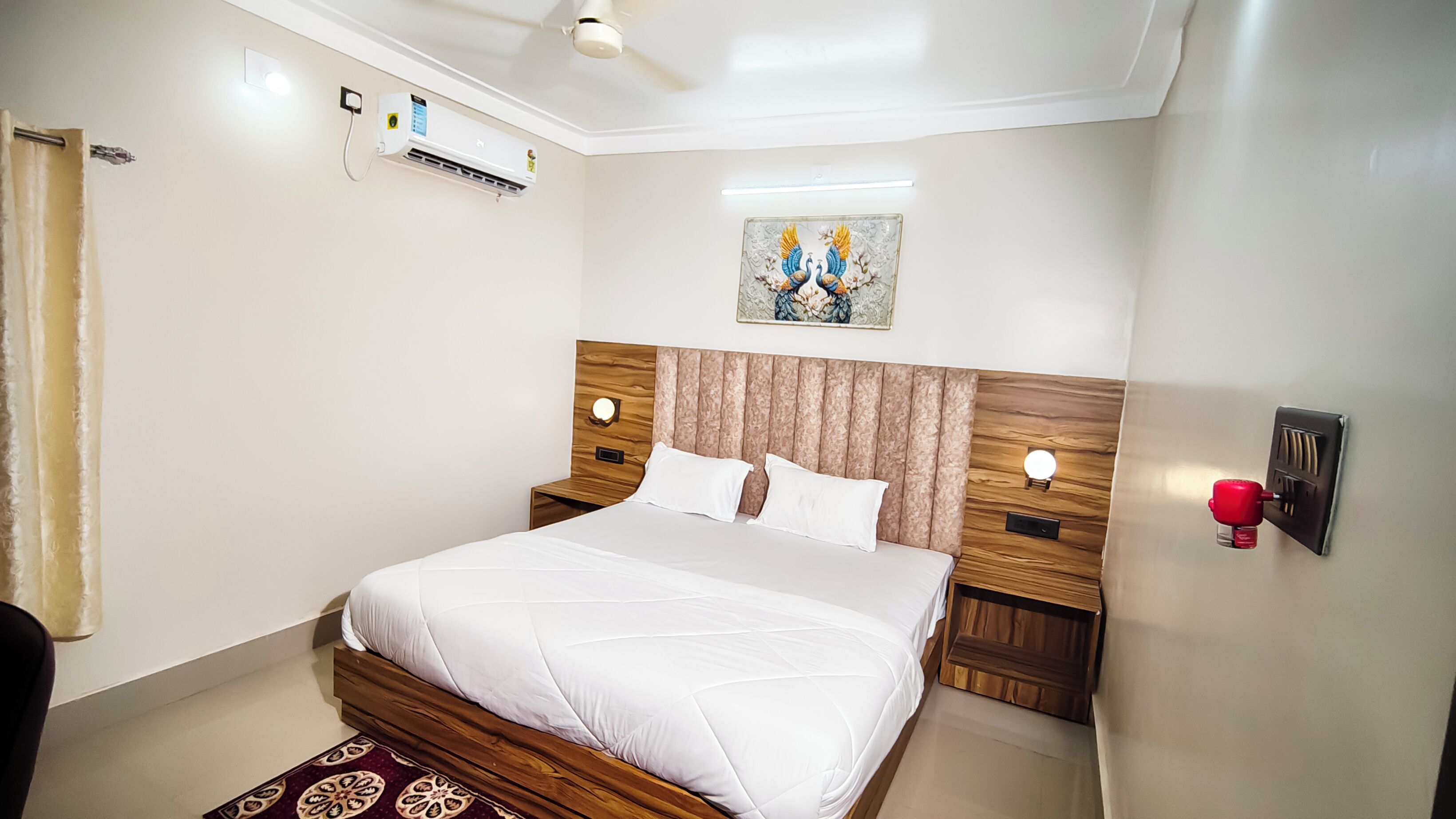 Ein Hotelzimmer mit einem Bett, einer Klimaanlage, einer Wandleuchte und einem Gemälde.