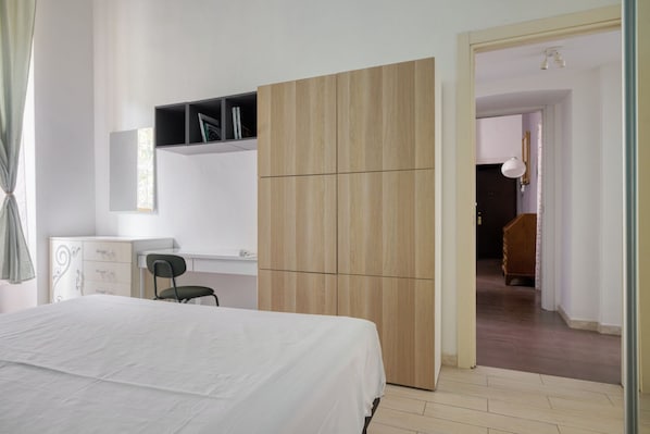 Ein Schlafzimmer mit Bett, Kleiderschrank, Schreibtisch und Stuhl.