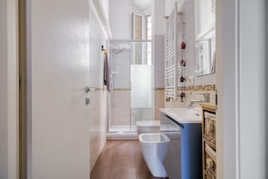 Ein modernes Badezimmer mit Duschkabine aus Glas, einer weißen Toilette und einem Waschbecken mit blauer Arbeitsplatte.