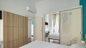 Um quarto com uma cama, um guarda-roupa, um espelho e uma escrivaninha.