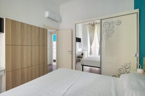 Ein Schlafzimmer mit Bett, Kleiderschrank, Spiegel und Schreibtisch.
