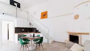 Un interior moderno con comedor, cocina, escalera y chimenea.