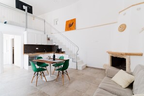 A modern interior with a dining area, kitchen, staircase, and a fireplace.