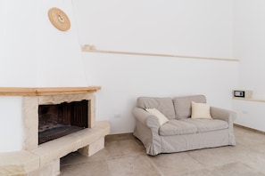 Una sala de estar con chimenea de piedra, un sofá beige y una estantería de madera.