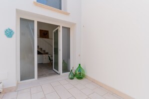 Pared exterior blanca con puerta corredera de vidrio que da a una escalera.