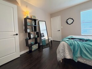 A bedroom with a bed, a dresser, a mirror, and a shelf with decorative items. - Serene & Secure Condo | Gated Community, Pool, Gym, and Dedicated Parking (Henderson)