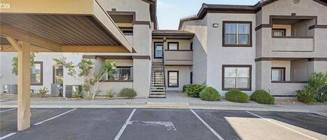 Um edifício residencial de vários andares com área de estacionamento coberta.