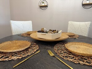 A round dining table with woven placemats, a central white bowl with decorative items, and matching wall-mounted shelves. - Serene & Secure Condo | Gated Community, Pool, Gym, and Dedicated Parking (Henderson)
