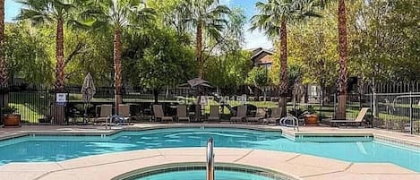 A swimming pool with lounge chairs and palm trees.