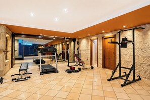Un gimnasio con equipo de ejercicio, una banca y una puerta que da a otra habitación.