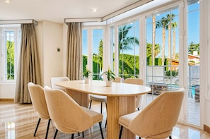 Un comedor moderno con una mesa redonda, seis sillas y plantas en macetas.