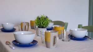 Une table à manger avec des bols, des tasses et une petite plante en pot.