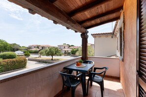 A covered balcony with a table and chairs, overlooking a residential area with houses and greenery. - Casa Dell Edera F2 1 by Wonderful Italy (San Teodoro)