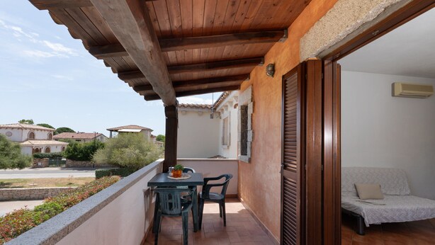 Un balcon doté d’un plafond en bois, une table avec des chaises, un lit et une vue sur les environs.