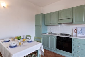 A kitchen with green cabinets, a stove, and a sink. - Casa Dell Edera F2 1 by Wonderful Italy (San Teodoro)
