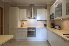 Een moderne keuken met witte kasten, roestvrijstalen apparatuur en een ingebouwde oven.