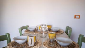 A dining table set with bowls, mugs, and a pitcher, surrounded by green chairs.