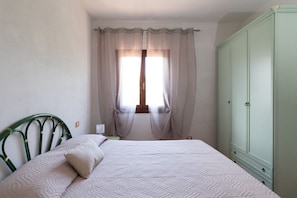 Ein Schlafzimmer mit einem Bett, einem Kleiderschrank und einem Fenster mit Vorhängen.
