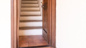 Una puerta de madera que da a una escalera con piso de baldosas.