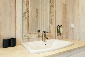 Ein Badezimmer mit einem weißen Waschbecken, einem Spiegel und zwei schwarzen Behältern auf der Ablagefläche.