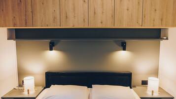 Una cama doble con ropa blanca, dos lámparas de noche y un cabecero de madera.