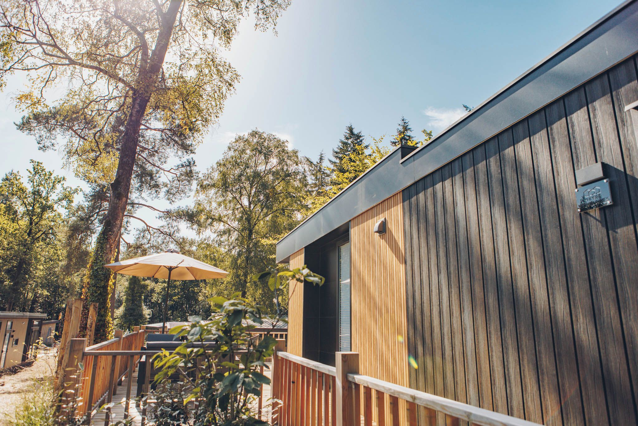 A wooden building with a balcony, surrounded by trees and a clear sky.