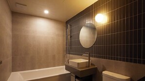 A modern bathroom with a bathtub, a sink, a toilet, and a mirror on the wall. - Lereve Hotel (Seoul)