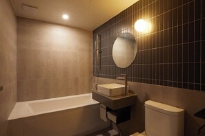 Un baño moderno con bañera, lavabo, inodoro y un espejo en la pared.
