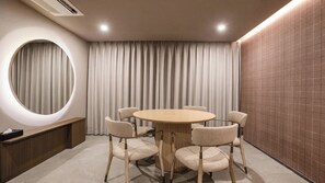 A conference room with a round table, six chairs, a large mirror, a curtain, and a brick wall. - Lereve Hotel (Seoul)