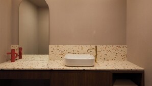 A bathroom with a rectangular sink, a mirror, and a wall-mounted towel rack. - Lereve Hotel (Seoul)